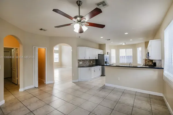 a view of a kitchen with kitchen island stainless steel appliances a sink and a counter top space