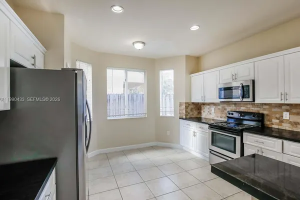 a kitchen with stainless steel appliances granite countertop a refrigerator stove top oven and sink