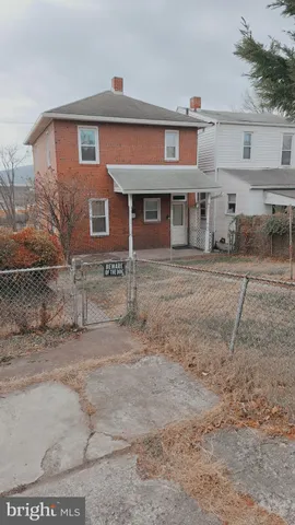 a front view of a house with a dirt yard and a large tree