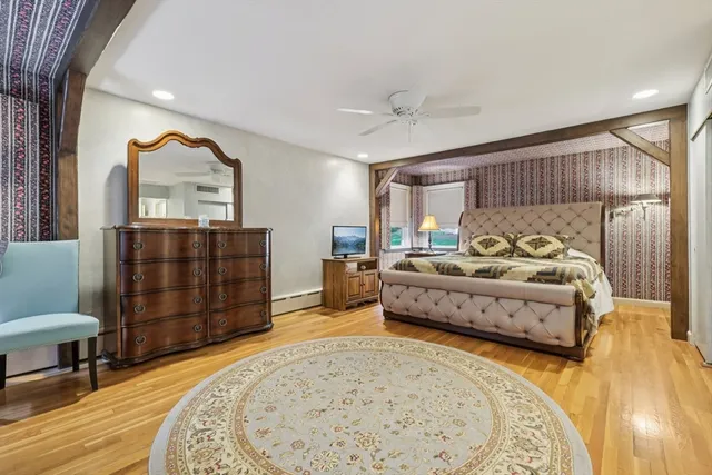 a spacious bedroom with a bed a dresser and wooden floor