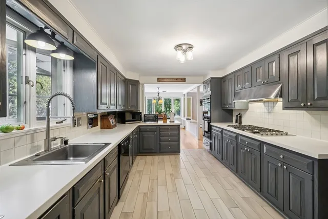 a kitchen with kitchen island granite countertop a sink stainless steel appliances wooden floor and cabinets