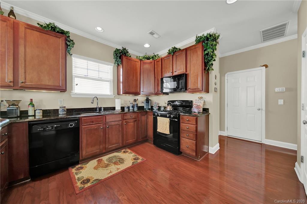 320 Sand Paver Way Fort Mill, SC 29708 - Photo 14 of 42 a kitchen with kitchen island granite countertop wooden floors stainless steel appliances a sink and a window