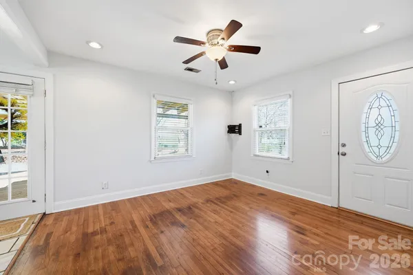 a view of an empty room with window and wooden floor