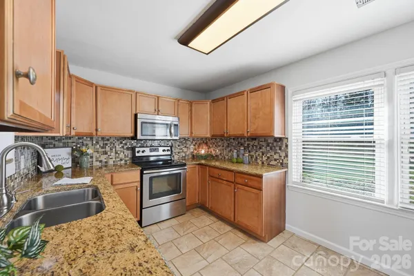 a kitchen with stainless steel appliances granite countertop a stove a sink and a microwave