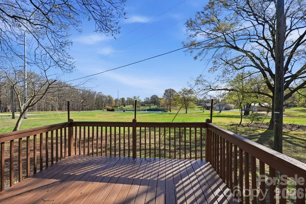 a view of a roof deck with large trees and wooden fence
