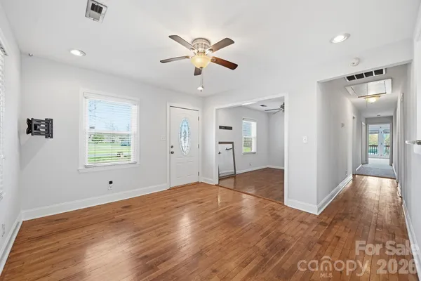 a view of empty room with wooden floor and fan