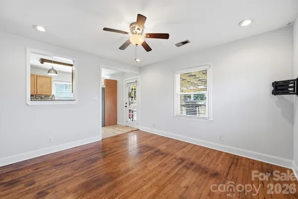 a view of an empty room with wooden floor and a window