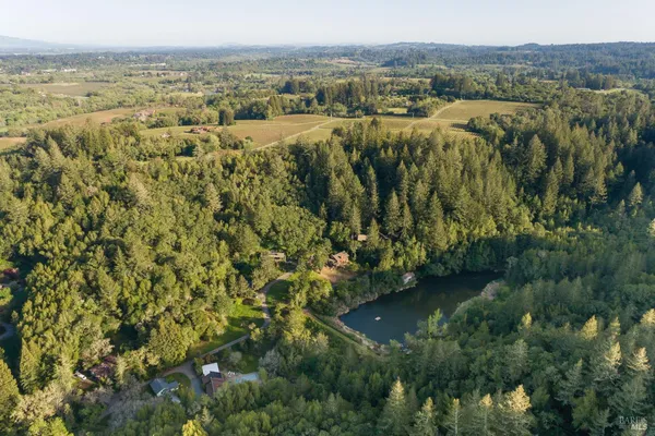 an aerial view of residential house with outdoor space and trees all around