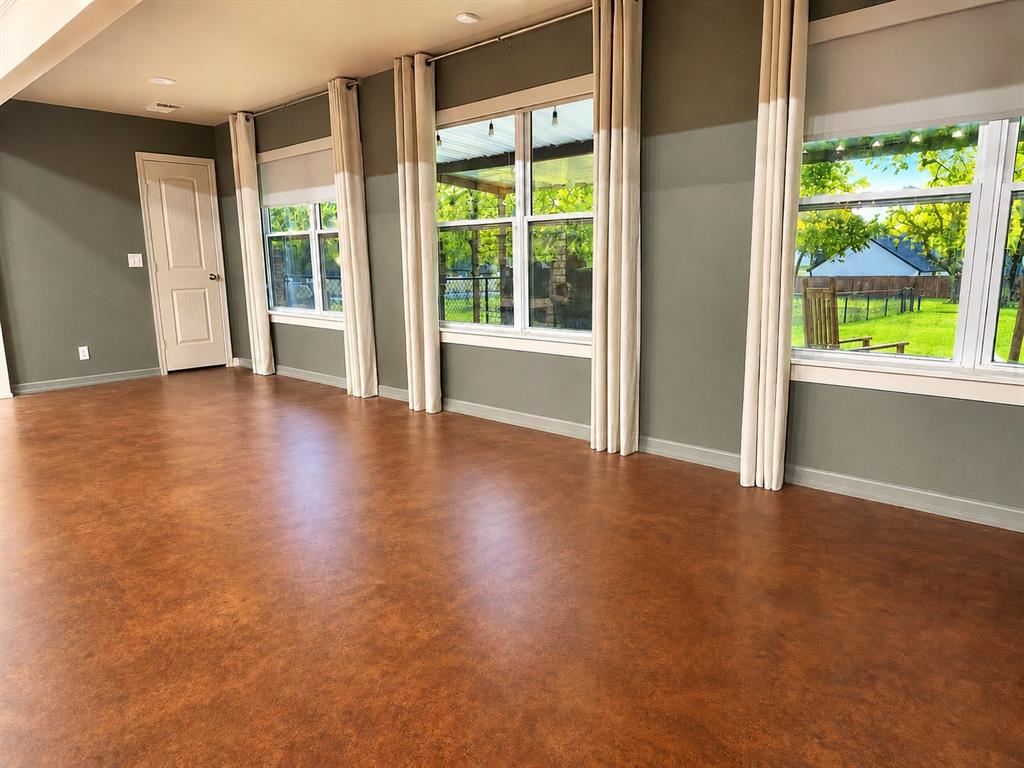 420 Sessums Road Springtown, TX 76082 - Photo 8 of 40 Spacious room featuring rich brown flooring, a two-tone painted wall, recessed lighting, and multiple windows overlooking a grassy outdoor space
