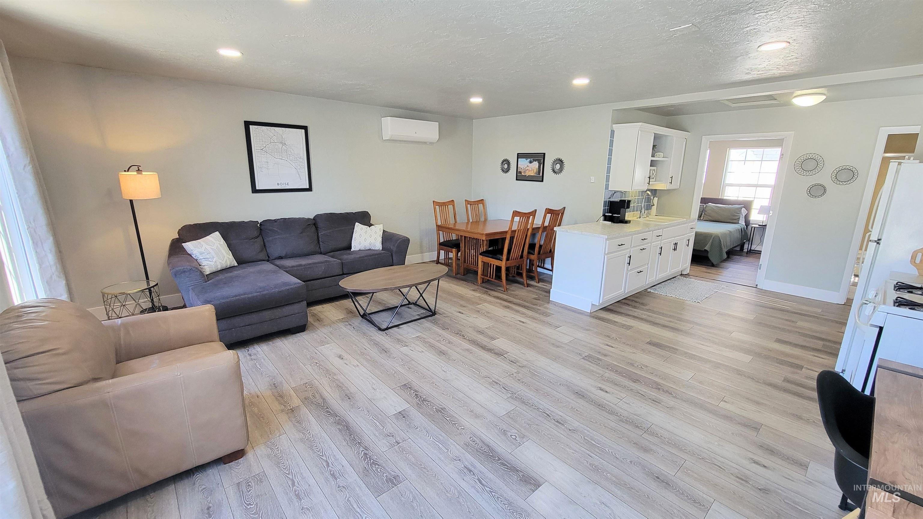814 Baker Street Boise, ID 83706 - Photo 16 of 26 Open-concept living area featuring light wood-finish flooring, recessed ceiling lighting, a dedicated dining space with a wooden table, a kitchen island with white cabinetry, and a mini-split climate control system