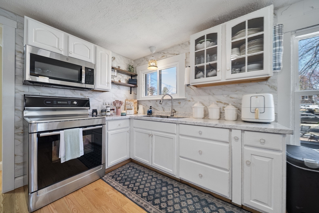 294 Whalom Road Lunenburg, MA 01462 - Photo 11 of 32 a kitchen with stainless steel appliances a stove a microwave and sink