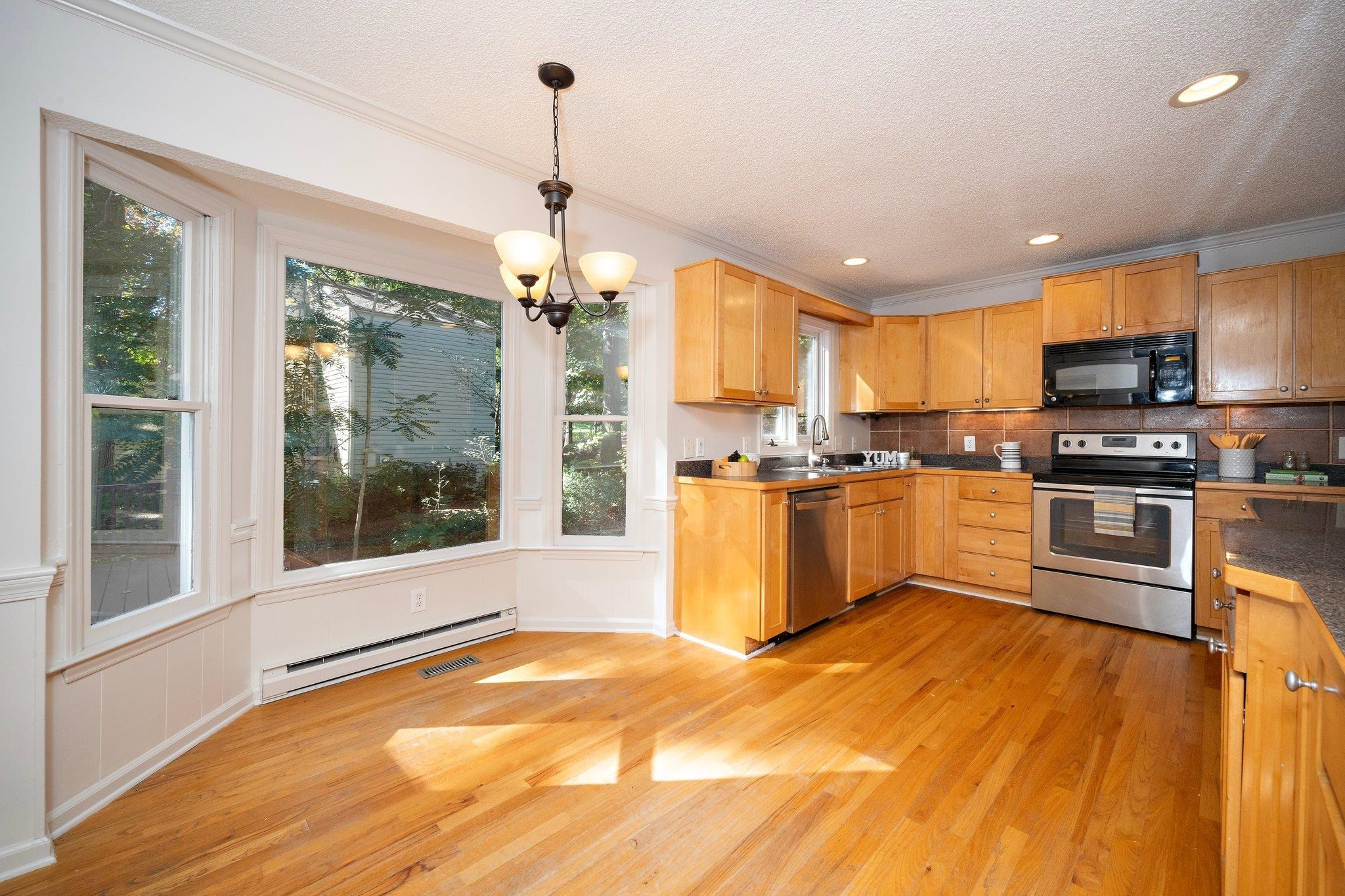 6304 Rushingbrook Drive Raleigh, NC 27612 - Photo 20 of 51 a kitchen with stainless steel appliances granite countertop a refrigerator a sink dishwasher a stove and white cabinets with wooden floor