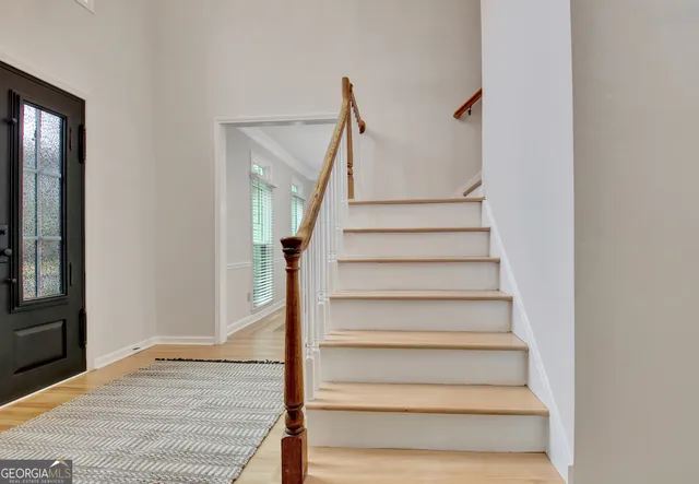 an empty room with wooden floor chandelier fan and windows