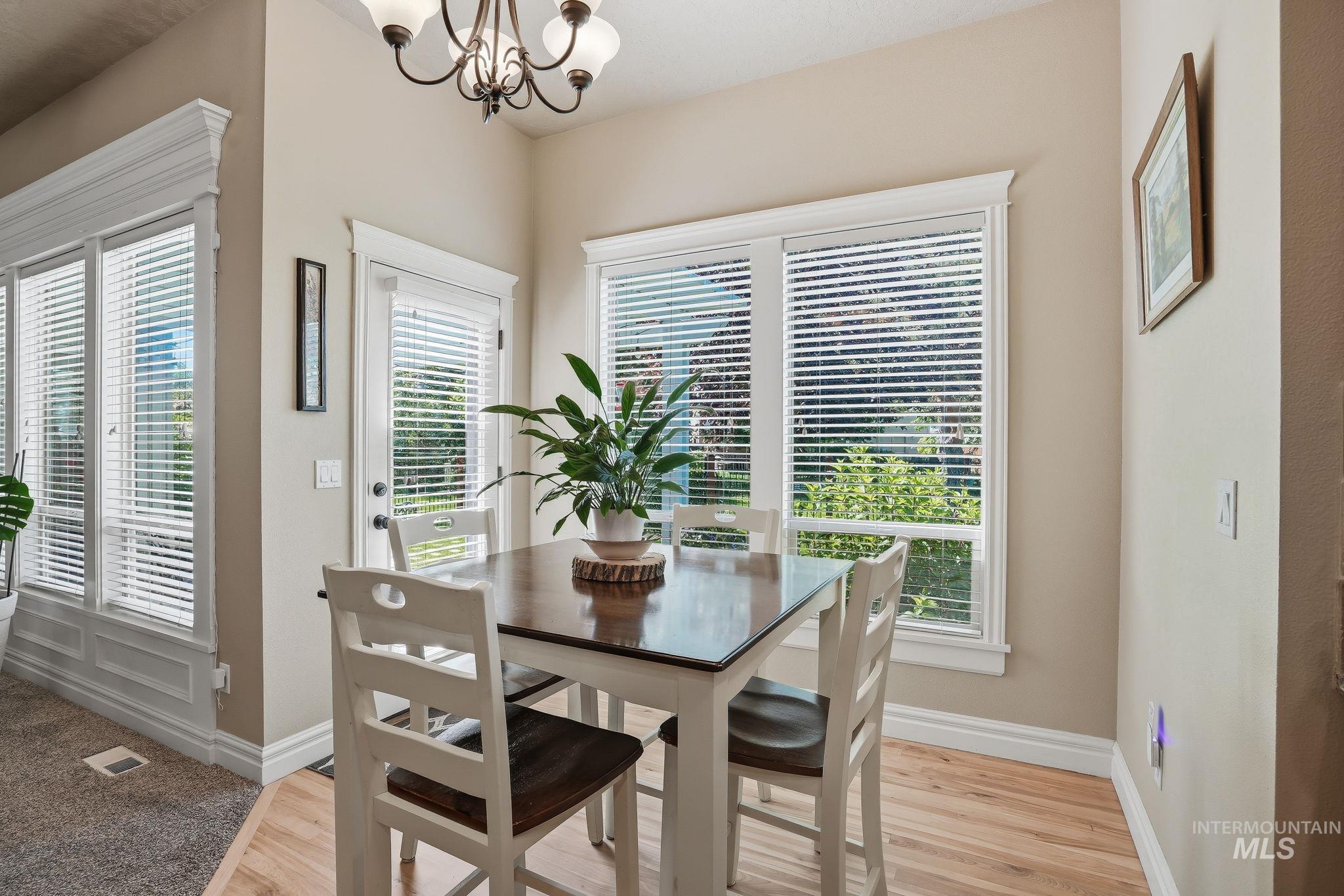 3969 North Hollymount Way Meridian, ID 83646 - Photo 17 of 47 Dining area featuring wood-finish flooring, a multi-pane window with white trim, a glass-paned door, and a chandelier
