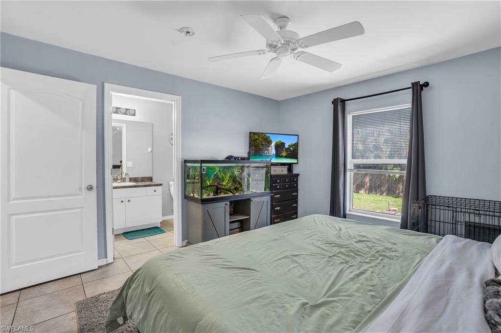 8069 Albatross Road Fort Myers, FL 33967 - Photo 14 of 21 Bedroom with sink, light tile patterned floors, ensuite bath, and ceiling fan