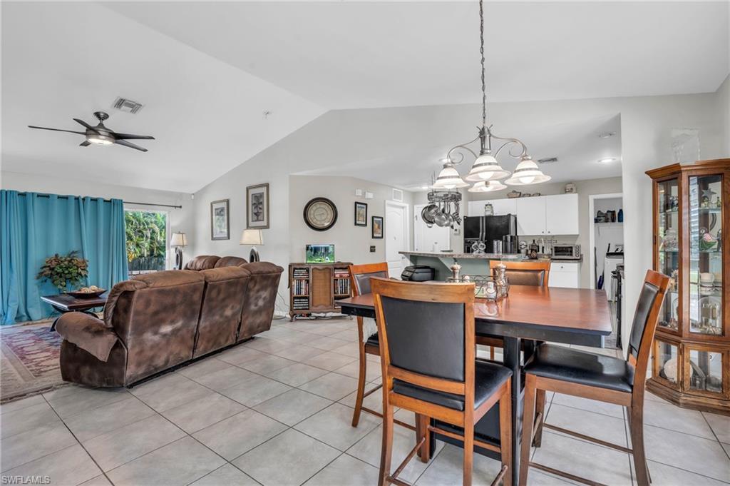 8069 Albatross Road Fort Myers, FL 33967 - Photo 6 of 21 Tiled dining space with ceiling fan with notable chandelier and vaulted ceiling