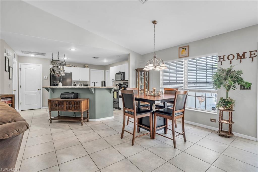 8069 Albatross Road Fort Myers, FL 33967 - Photo 7 of 21 Dining space featuring light tile patterned flooring, an inviting chandelier, and vaulted ceiling
