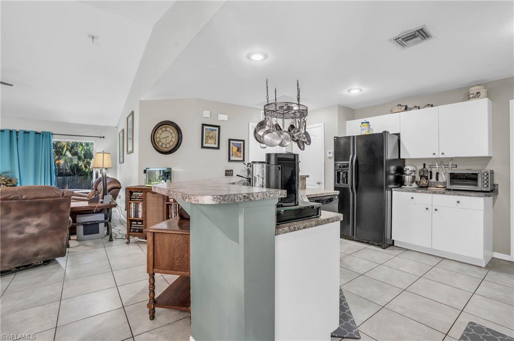 8069 Albatross Road Fort Myers, FL 33967 - Photo 8 of 21 Kitchen featuring white cabinetry, lofted ceiling, light tile patterned floors, and black refrigerator with ice dispenser