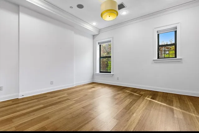a view of a hallway with wooden floor and a bathroom