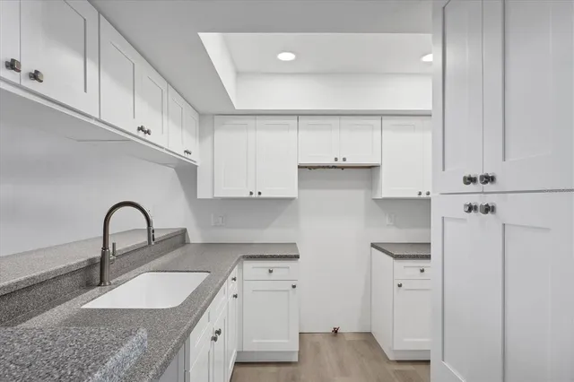 a kitchen with granite countertop a sink and dishwasher with white cabinets