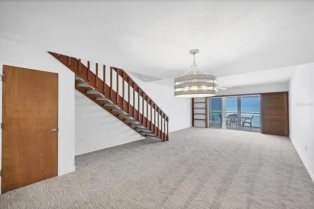 a view of an empty room with wooden floor and stairs