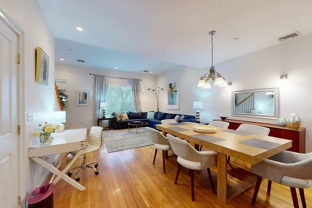 a view of a dining room and livingroom with furniture wooden floor a chandelier