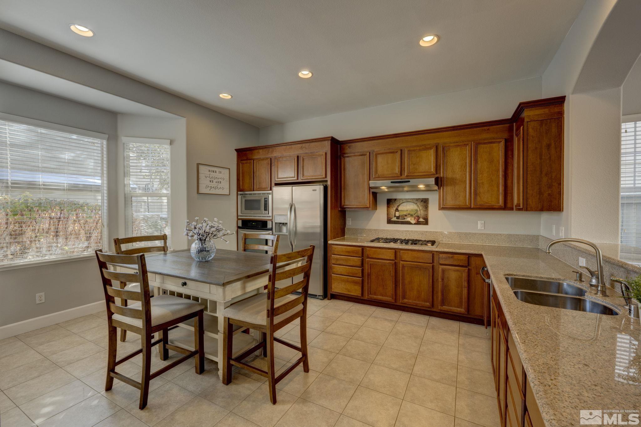7669 Stone Bluff Way Reno, NV 89523 - Photo 9 of 40 a kitchen with stainless steel appliances granite countertop a stove a sink a microwave a dining table and chairs