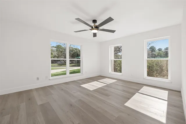 a view of an empty room with a window and wooden floor