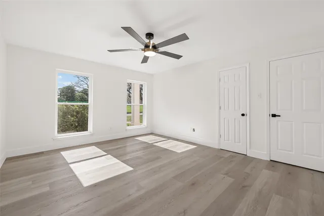 a view of empty room with wooden floor and fan