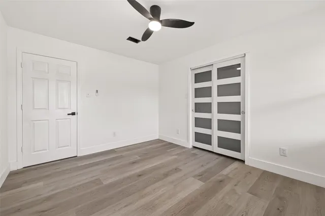 a view of an empty room with wooden floor closet and windows
