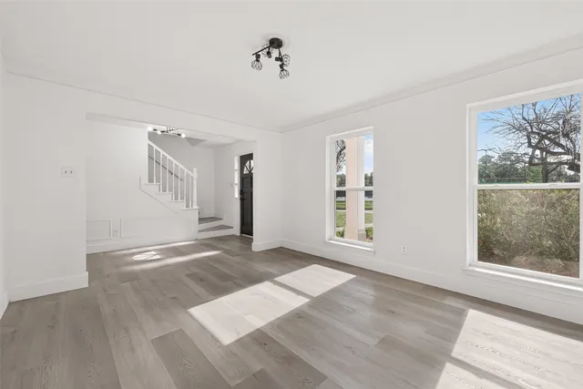 a view of an empty room with window and wooden floor