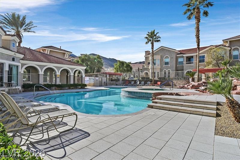 10550 West Alexander Road, Unit 2148 Las Vegas, NV 89129 - Photo 15 of 41 A refreshing resort-style pool and spa await, surrounded by mature palm trees and Mediterranean-inspired architecture.
