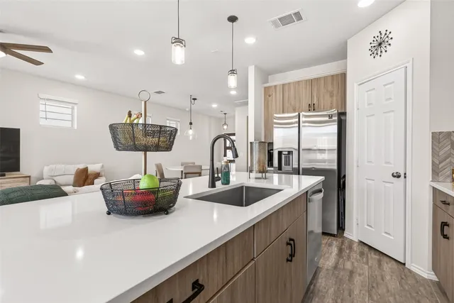 a kitchen with stainless steel appliances a sink a counter space and living room view
