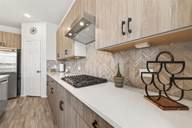 a kitchen with stainless steel appliances granite countertop a lot of cabinets and wooden floor