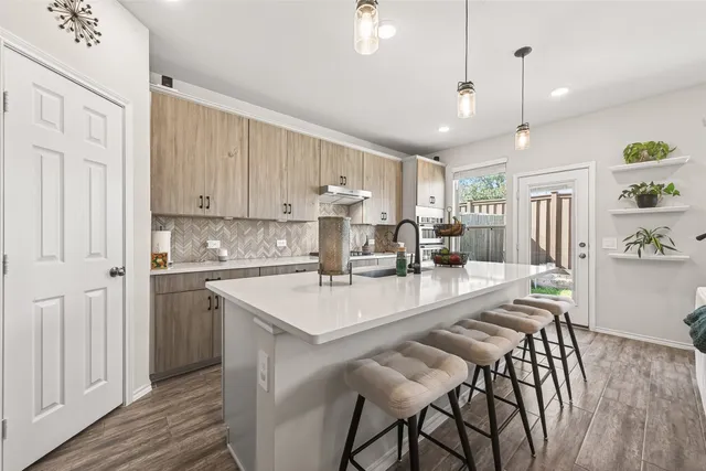 a large white kitchen with wooden floor and stainless steel appliances