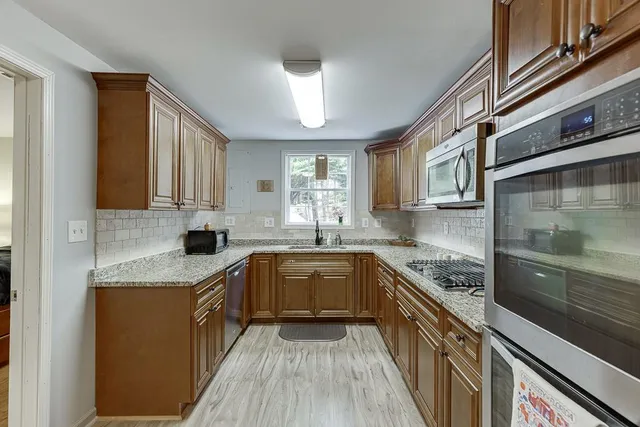 a kitchen with granite countertop a sink stove top oven and cabinets