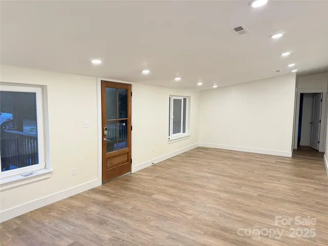 a view of an empty room with wooden floor and a window