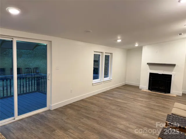 an empty room with wooden floor fireplace and windows
