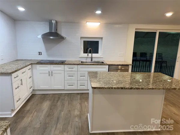 a kitchen with stainless steel appliances granite countertop a sink a stove and a wooden floors