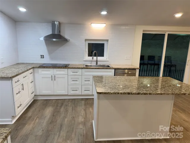 a kitchen with stainless steel appliances granite countertop a sink a stove and a wooden floors