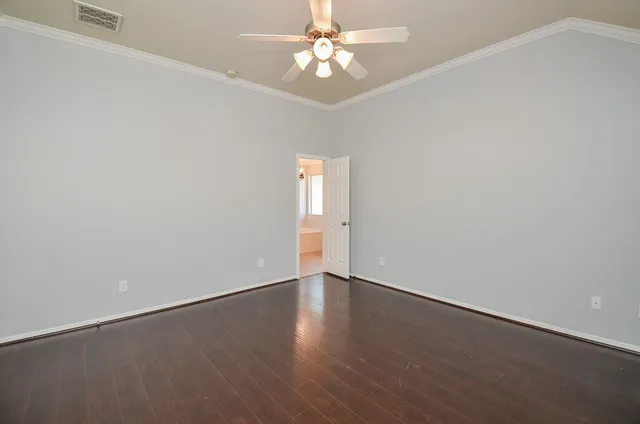 an empty room with wooden floor chandelier fan and windows