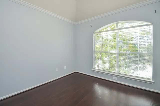 an empty room with wooden floor chandelier fan and windows