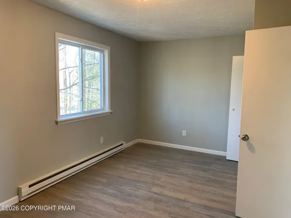 a view of empty room with wooden floor and fan