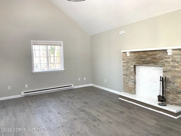 an empty room with wooden floor mirror and windows