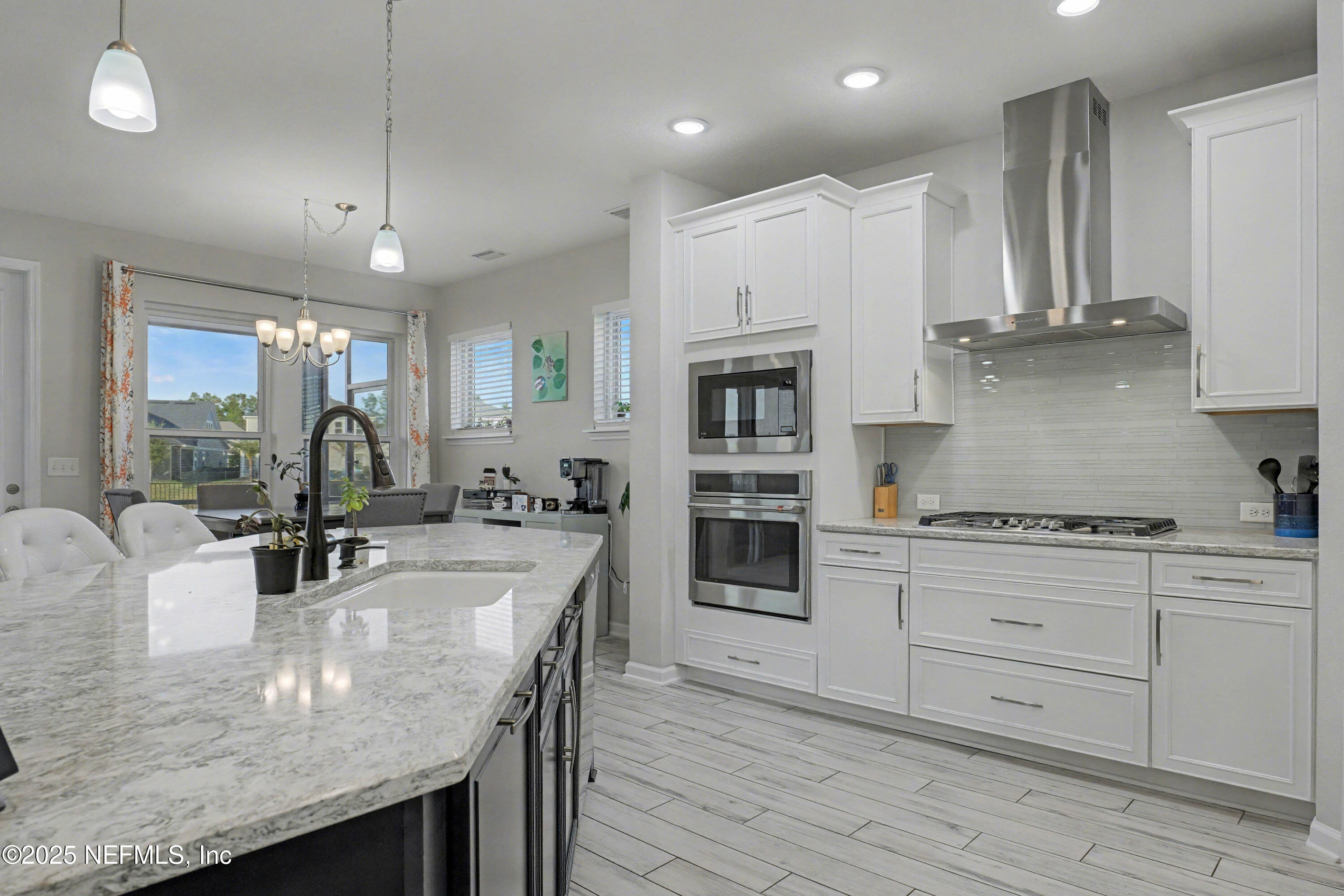 139 Spinner Drive Ponte Vedra, FL 32081 - Photo 18 of 67 a kitchen with kitchen island granite countertop wooden floors and white cabinets