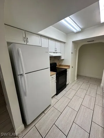 a kitchen with a refrigerator sink and cabinets
