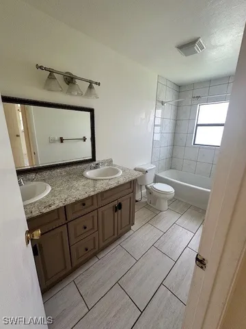a bathroom with a granite countertop sink and a toilet