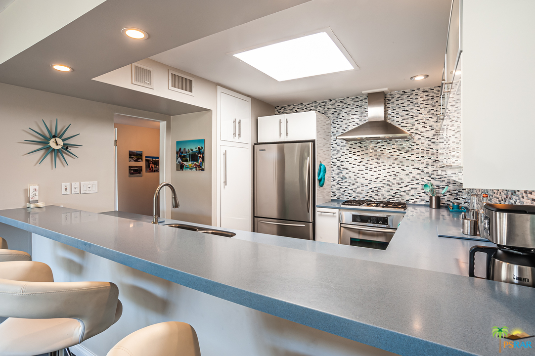 1805 Sandcliff Road Palm Springs, CA 92264 - Photo 23 of 51 a kitchen with stainless steel appliances kitchen island granite countertop a refrigerator a stove and a sink with wooden floor