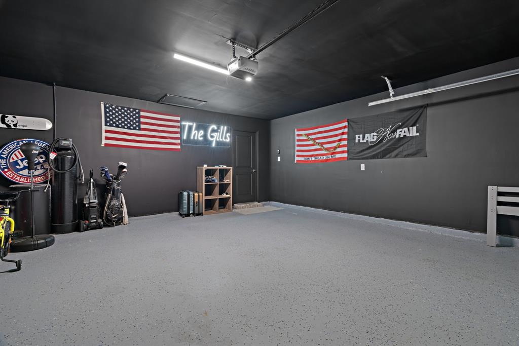 3112 Kingsgarden Road Denton, TX 76207 - Photo 33 of 38 Spacious garage with dark painted walls and ceiling, featuring an overhead garage door opener
