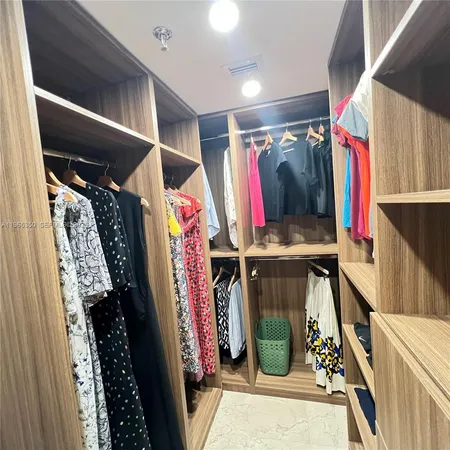 a view of walk in closet with clothes and shoes
